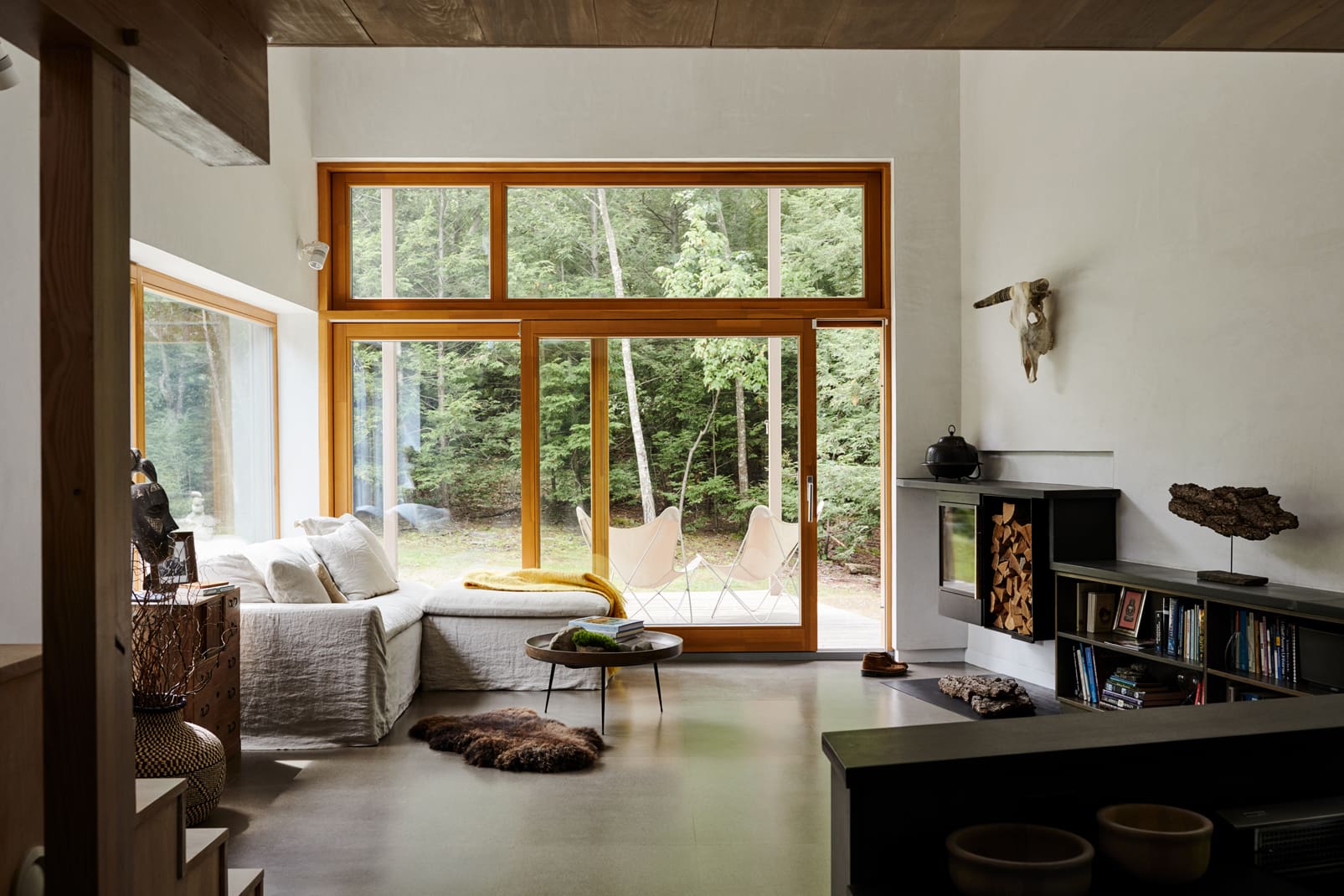 A modest, open living room with large glass sliding doors looking out to the deck and the woods beyond