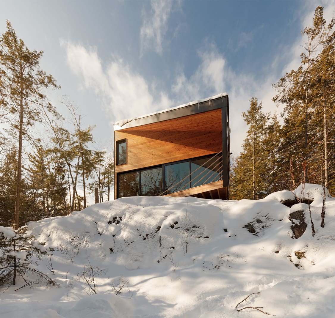 Front view of an angular tiny house on a snowy hill