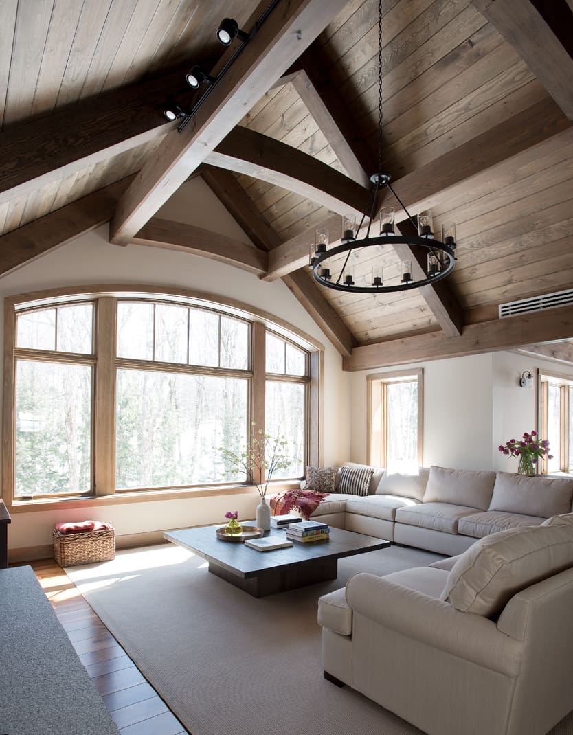 A vaulted timber frame ceiling and a bank of windows frame a modern living room