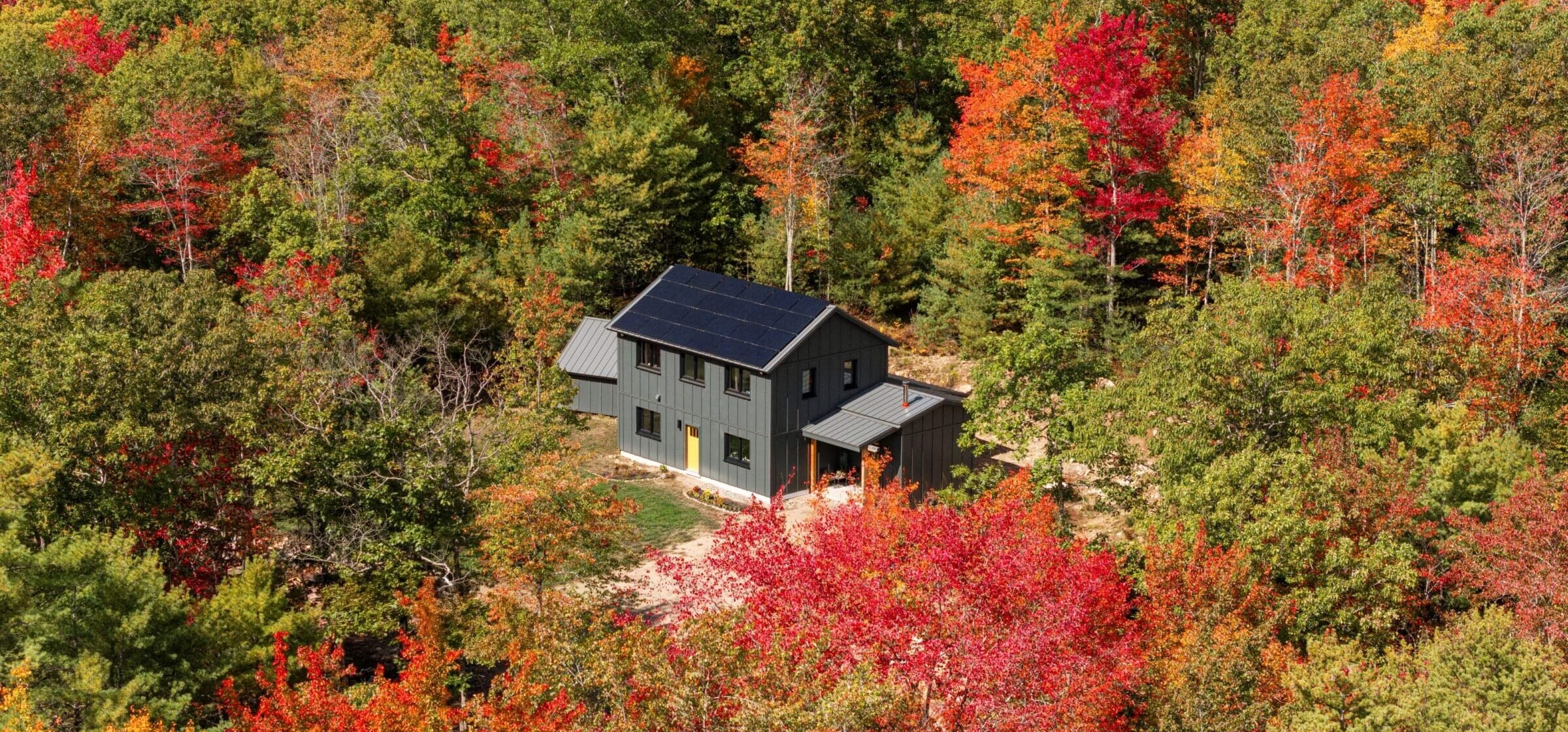 Aerial view of a grey Unity Homes Varm Gavle surrounded by fall foliage.